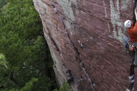 Rock climber climb crevice in rock face.