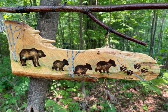 Wood sign art piece showing four bears and bear prints.
