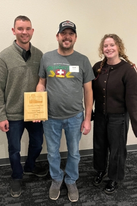New Glarus staff posing with supervisor staff while holding award plaque.