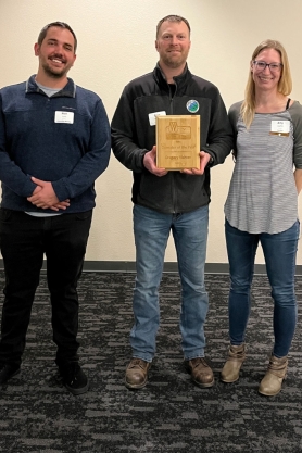 Gregory Richter holding his award plaque while posing with wastewater supervisors.