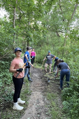 group shovels and clears trail, smiling at photographer.