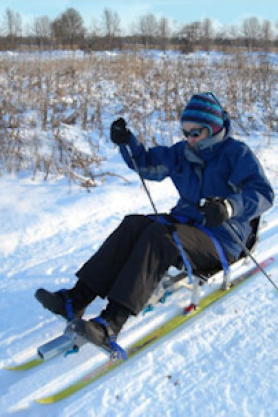 Jane Schmieding using one of the cross-country sit skis at Governor Nelson State Park on a snowy winter day. Jane has MS which restricts her ability to walk.