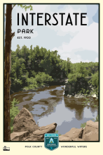 Rocky overlook of river and forest labeled Interstate Park Est. 1900.