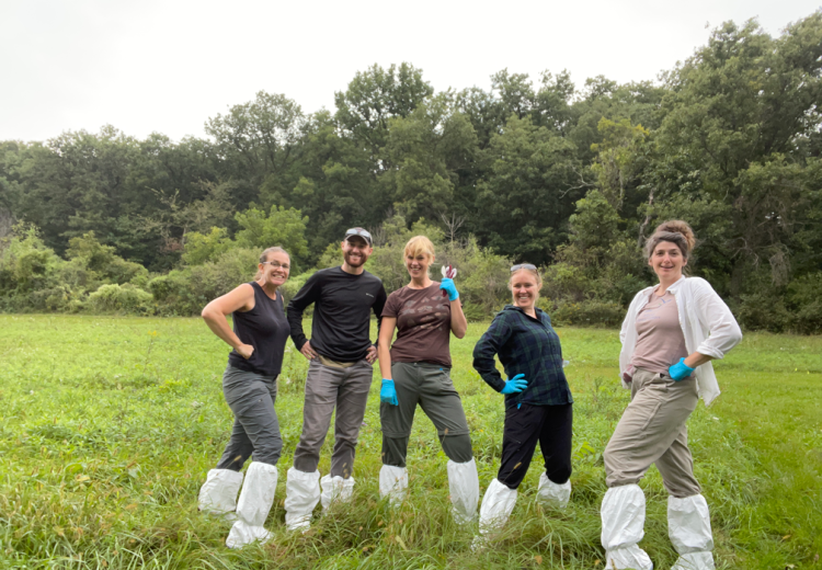 Dr. Wendy Turner poses with members of her lab in a grassy field.