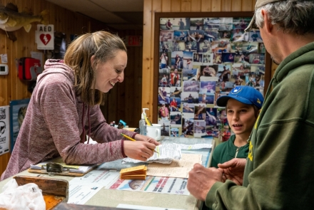 Photo Description: NHFRA staff jot down information after a young angler and his father return from a successful fishing trip.
