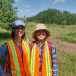 Snapshot team member and an intern smile for the camera, wearing blaze orange as they search for elk calves to collar.