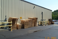 Image of clean wooden pallets stacked against a building.