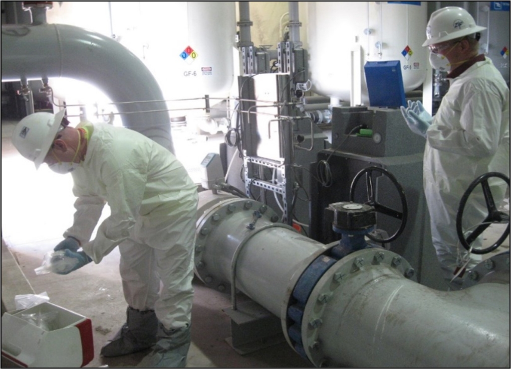 Two staff dressed in PPE collecting samples of processed water for testing. Photo: The Boldt Co.