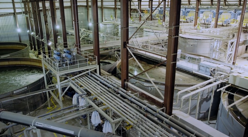 View inside the Sediment Processing Facility. Water tank clarifiers in the foreground, sediment plate presses (blue) in the far background. Photo: Boskalis