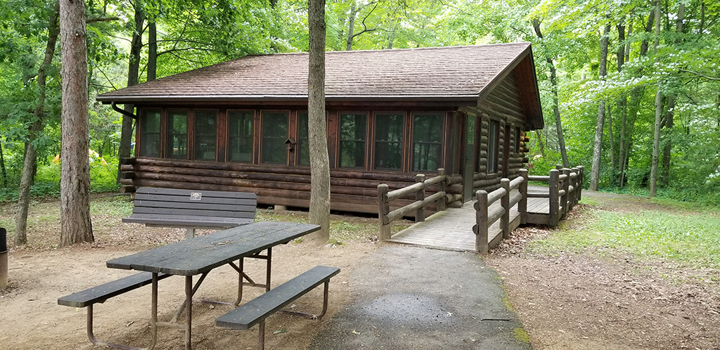 The accessible log cabin nestled in the forested campground at Mirror Lake State Park.