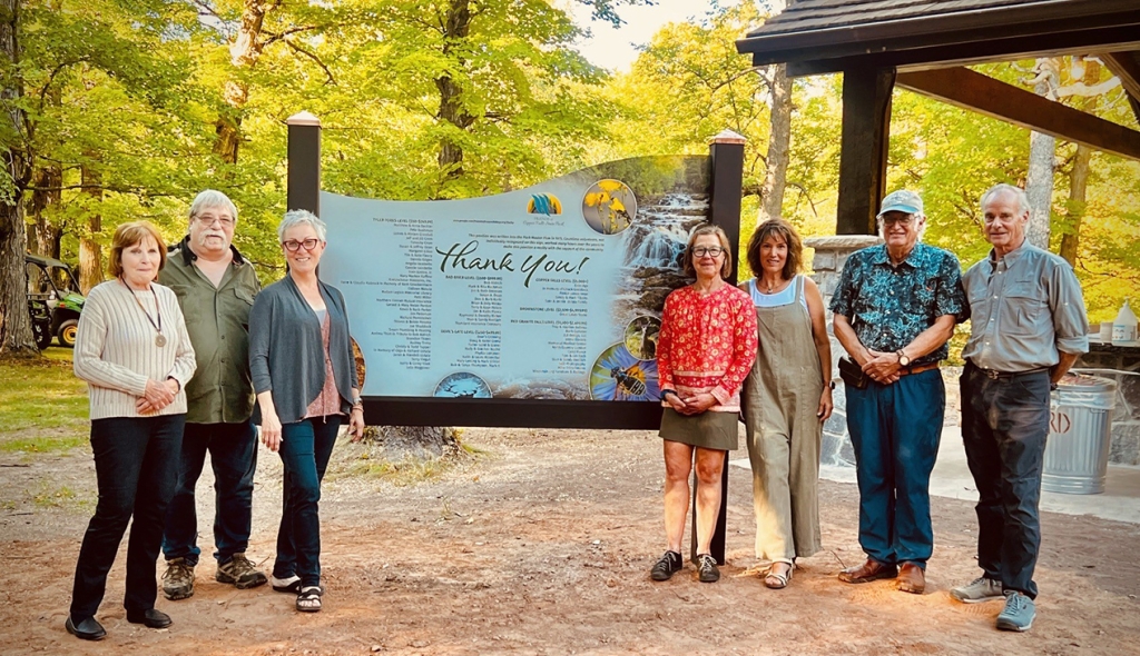 A group of Friends Group Volunteer standing in front of a large sign thanking all of the Park volunteers.