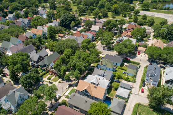 An aerial view of a forested urban neighborhood.